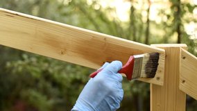 Adult craftsman carpenter with the brush painting the boards of a wooden fence. Housework, do it yourself. Footage.