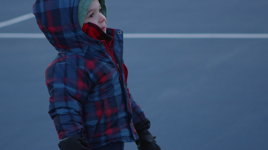 Young boy playing in tennis court in late autumn - being silly spinning around