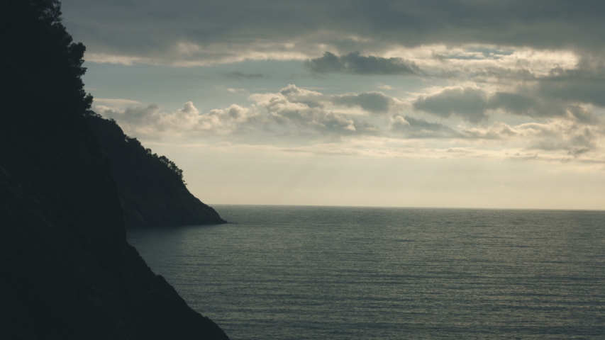 Coast silohuette under dramatic sky over the horizon with calm sea