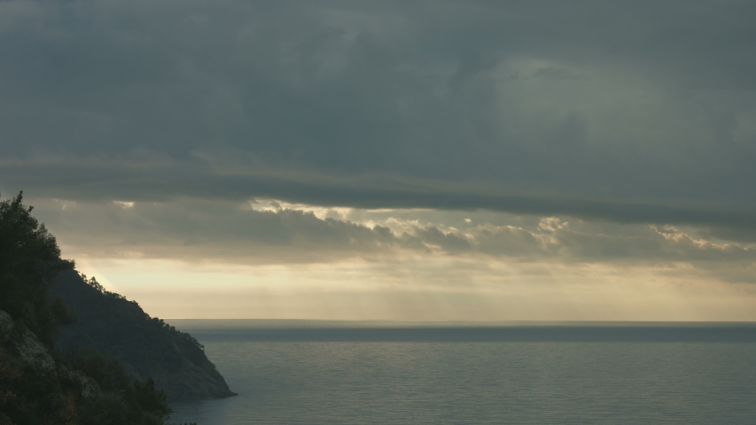 Coast silohuette under dramatic sky over the horizon with calm sea