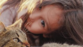Cute little girl hugging cat  on grass. Lifestyle child and animal timespending video.