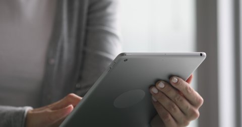 Close up view of business woman holding digital tablet in hands using business apps typing studying online at home office, computer device for modern professional communication digital work concept