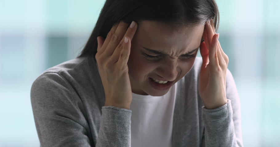 Upset sick young woman coping with terrible headache feel migraine, stressed tired girl frustrated suffer from pain ache pressure touching aching sore head at home office concept, face close up view Royalty-Free Stock Footage #1037145032