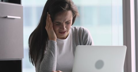 Stressed young business woman feeling headache migraine or eye strain working on laptop in office, upset frustrated lady suffer from pain coping with blood pressure tired of computer syndrome concept