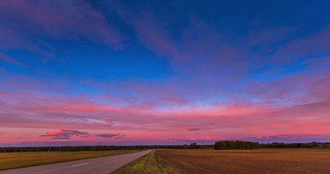 Red sunset sky time lapse with a road. Clouds timelapse nature background. Dramatic evening color beauty. Twilight, dusk dawn, summer.