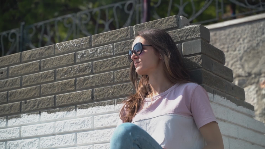 Beautiful young brunette girl and sunglasses closeup turns on the camera and shows the middle finger