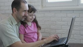 A man with a child at the computer. A freelancer father works on a computer with his daughter.