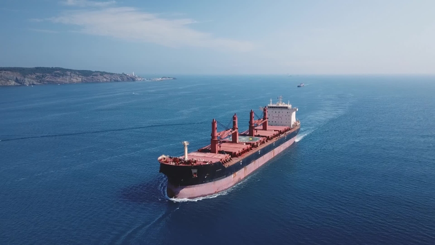 Flying over a cargo ship cruising northbound on Straits Bosporus. A bulk carrier or bulker is a merchant ship specially designed to transport unpackaged bulk cargo, such as grains, ore, coal or timber Royalty-Free Stock Footage #1037150894