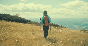 Woman backpacker tourist traveler camper walking on the top of mountain in summer sunny day under sun light. Beautiful mountains landscape view. 4K slow motion video