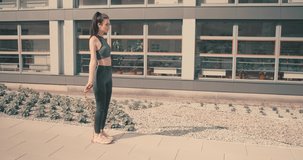 Young woman doing sports in outdoors modern place in city park in summer sunny day under sun light. 4K slow motion video