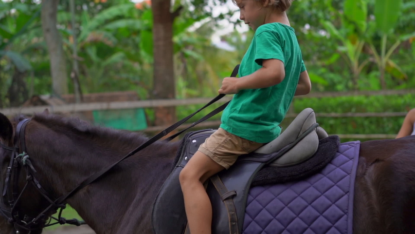 Slowmotion shot of a little boy having a horseridding lesson