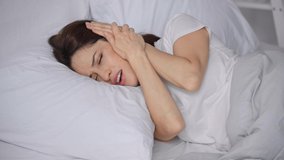 woman lying in bed and suffering from noise