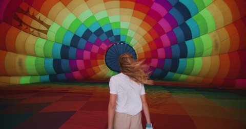 Authentic slow motion of young female pilot is entering inside of colorful hot air balloon during inflation before the flight.
