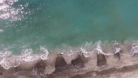 Fixed shot and top view of a tropical beach. Ocean waves crashing against the beach from above.