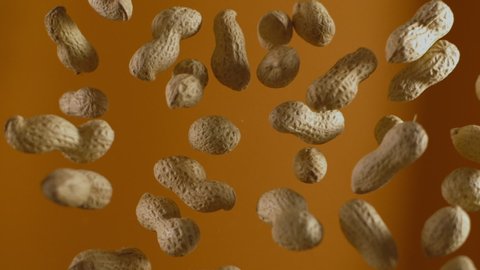 Falling peanuts in slow motion on the orange background, slow motion food, 240fps Full HD 10 bit