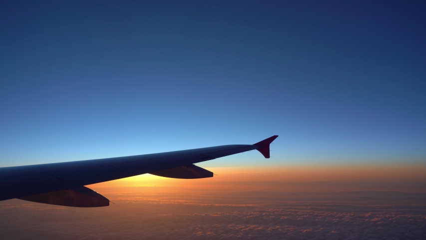 Up in the air, view of aircraft wing silhouette with dark blue sky horizon and cloud background in sun rise time, viewed from airplane window Royalty-Free Stock Footage #1037180579