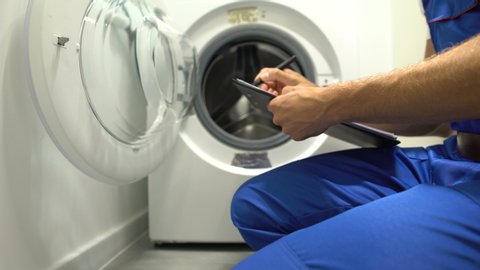 Man filling guarantee document for washing machine, maintenance and repair