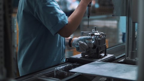 Industrial worker assembling metal appliances at automatical conveyor at factory. Close up engineer detailing electrical devices at production line on plant