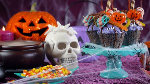 Happy Halloween candy land drip cake style cupcakes with lollipops and candy in party table setting.