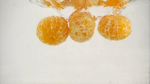 Purified tangerines slowly submerged in water, on a white background. Full HD Video. Theme of vegetarianism and raw food as a lifestyle. Fruit cocktail.