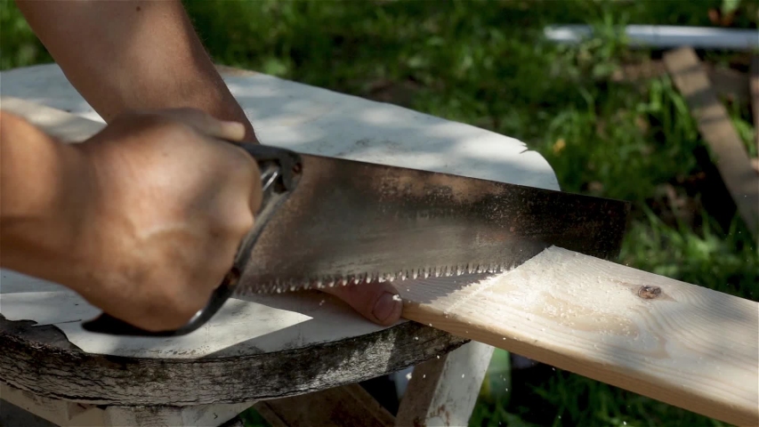 A man sawing wood Board with hand saw. Worker. Hard work