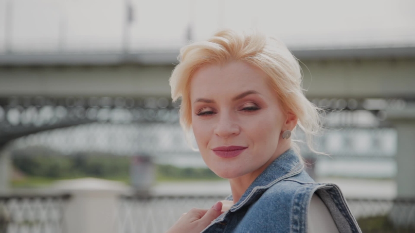 Beautiful young woman walks along the embankment by the river and enjoys what is happening.