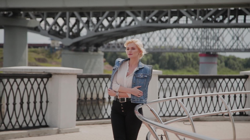 Beautiful young woman walks along the embankment by the river and enjoys what is happening.