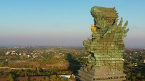 Bali's Most Iconic Landmark Hindu God Garuda Wisnu Kencana statue also GWK statue is a 122-meter tall statue located in Garuda Wisnu Kencana Cultural Park, Bali, Indonesia. 4k Aerial view at sunrise