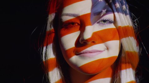 Close up slow motion shot of American flag projection on woman's face Video stock