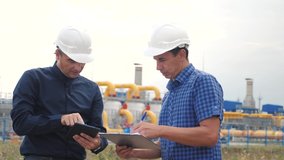teamwork gas production station concept. slow motion video. two engineers in helmets work at the station are studying on a gas supply lifestyle business contract. two workers work at the factory in