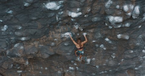 Aerial drone view of young fit woman lead rock climbing on an outdoors sport route, fast experienced rock climber