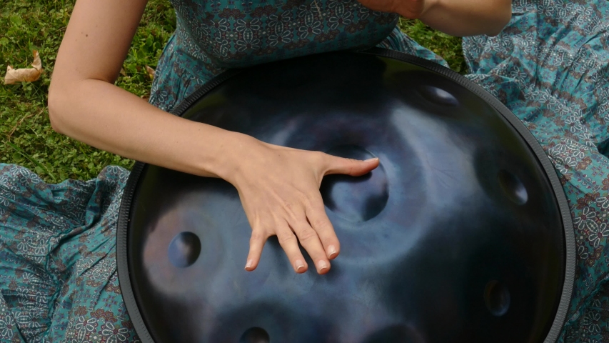 Woman hands plays on Swiss han drum outdoors