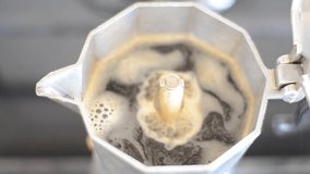 Coffee shoots from a small column with sprays and steam into a geyser-filled coffee machine. Close-up video with sizzling coffee sound