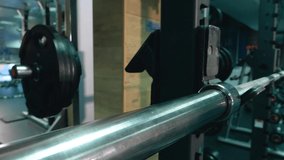 The girl puts a pancake on a barbell in the gym. Close-up of hands. Sports equipment.