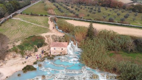 In Saturnia Italy, the drone rises up while tilting down revealing the entire hot spring baths.