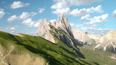 Aerial panoramic view of scenic landscape in the Alps with rugged alpine mountain peaks and lush blooming meadows on a sunny day with beautiful clouds and blue sky in summer