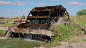Old Vintage Wooden Water Wheel Spins In Irrigation Ditch Against Blue Sky 10 Second Slow Motion Video.