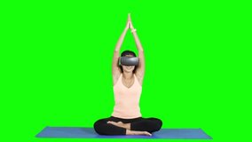 Young woman doing yoga exercise and meditating with Virtual Reality glasses in the studio. Shot in 4k resolution with green screen background - Powered by Shutterstock - Get 15% off with code: PIKWIZARD15