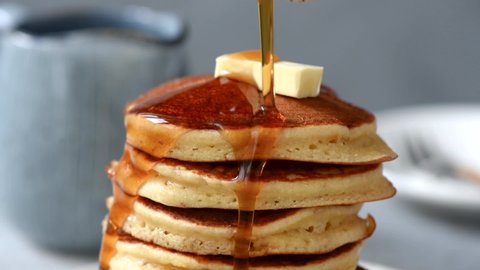 Pancakes with butter and maple syrup. Pouring syrup on american buttermilk pancakes