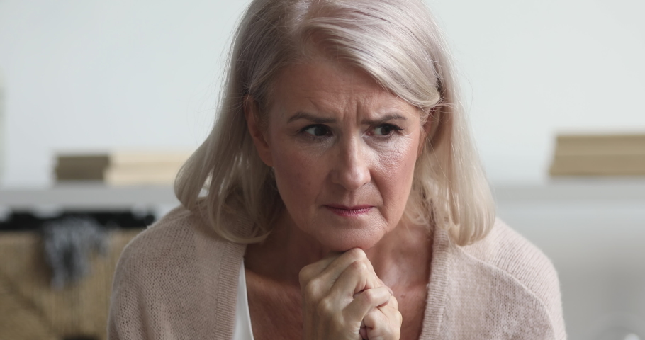 Thoughtful serious worried mature older lady feel concerned about health problems sit alone at home, anxious stressed pensive middle aged senior woman thinking of loneliness concept, close up view Royalty-Free Stock Footage #1037252561