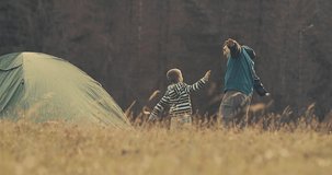 Happy traveler father and son bonding funny near tent camp around mountain under sun light enjoying the leisure and freedom. 4K slow motion video