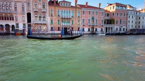 VENICE, Italy - May 2019: Gondolier leads the gondola through the grand channel. Inside is a couple in love. Slow motion.