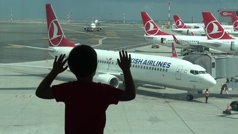 Istanbul Airport, Turkey - 18th of June 2019: 4K Impatient child watches Turkish Airlines planes and knocks the window
