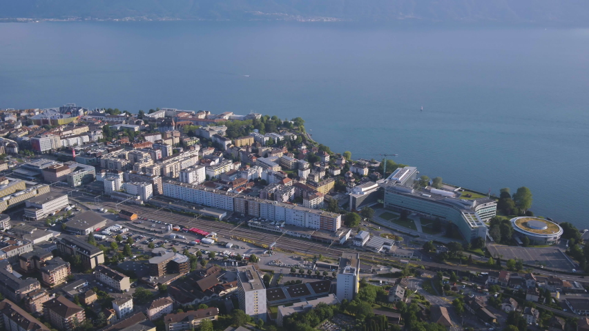 Aerial shot high over Vevey city, camera tilting upward revealing Lake Leman and Montreux area in background, Switzerland