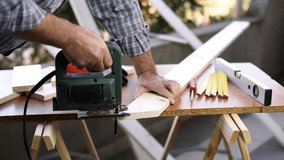 Adult craftsman carpenter with electric saw working on cutting a wooden table. Housework, do it yourself. Footage.