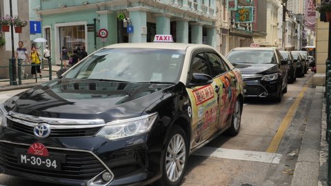 Slow motion shot of taxis slowly moving in a line on a busy and narrow road at Municipal Affairs Bureau, Macau (August 2019)
