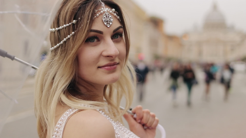 The face of a beautiful young girl with an umbrella on the background of the old town