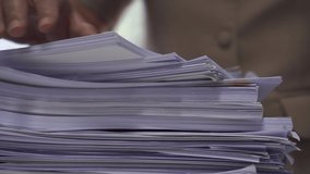 Businessman hands working in stacks of paper files for searching information on work desk office, business report papers,piles of unfinished documents achieves with clips indoor,Business concept