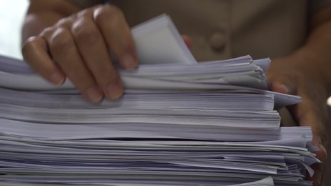 Businessman hands working in stacks of paper files for searching information on work desk office, business report papers,piles of unfinished documents achieves with clips indoor,Business concept
