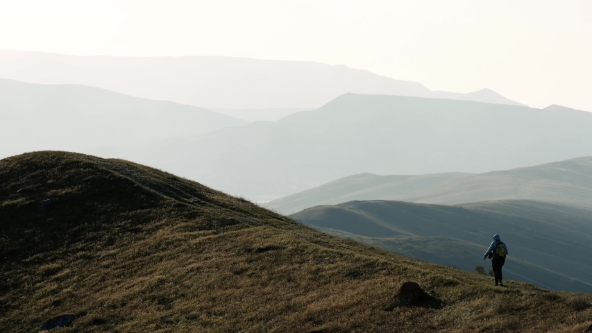 lonesome climber sitting on top of mountain. Adventurer in expedition. Freedom, zen concept